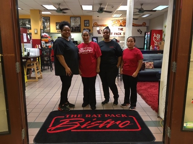 The four women of the Rat Pack Bistro team standing together behind their custom logo entrance mat The four women of the Rat Pack Bistro team standing together behind their custom logo entrance mat
