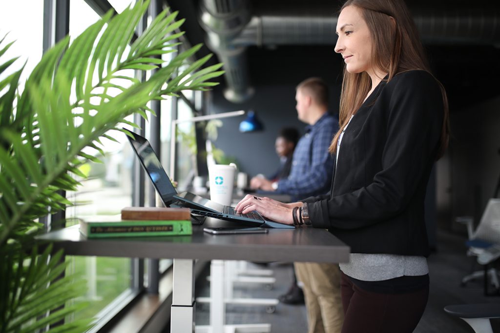 woman standing at sit-stand desk